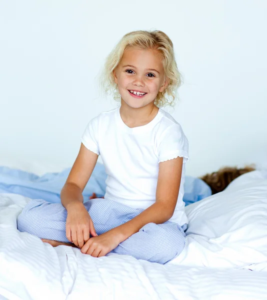 Blond meisje, zittend op bed — Stockfoto