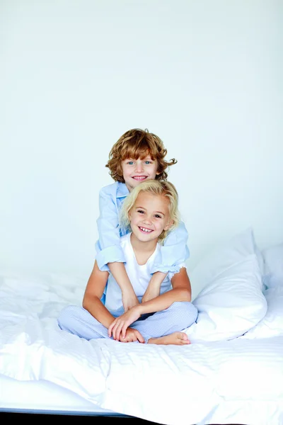 Sestra a bratr objímat v posteli — Stock fotografie
