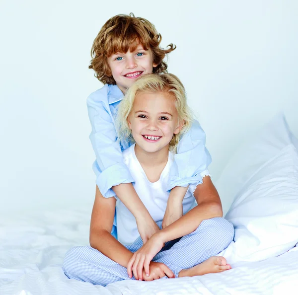 Mladší bratr všeobjímající svou malou sestru v posteli — Stock fotografie