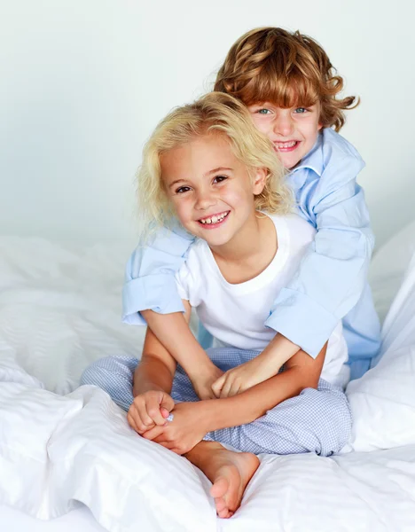 Liten flicka och en pojke på sängen — Stockfoto