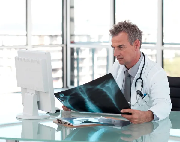 Fundersam manliga läkare tittar på sin dator — Stockfoto