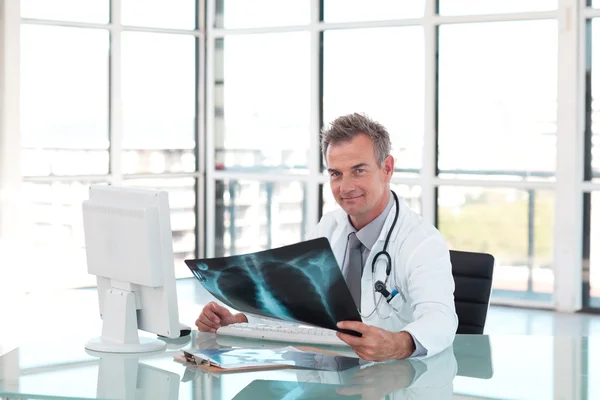 Ώριμη γιατρός κοιτάζοντας μια ακτινογραφία — Φωτογραφία Αρχείου