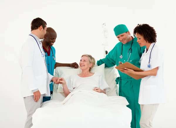 Idosos sorrindo paciente entre uma equipe médica — Fotografia de Stock