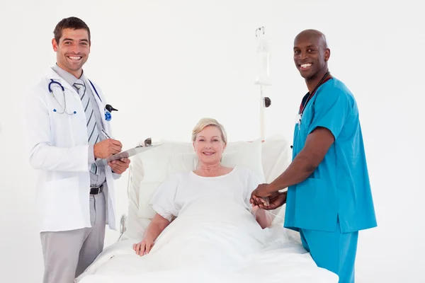 Tým lékařů s pacientem se usmívá na kameru — Stock fotografie