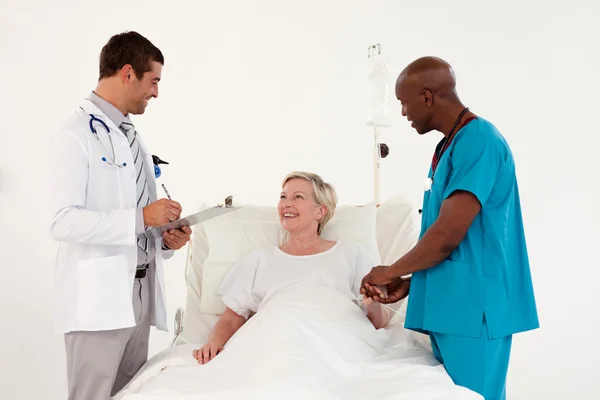 Smiling patient between a male doctor and surgeon — Stock Photo, Image