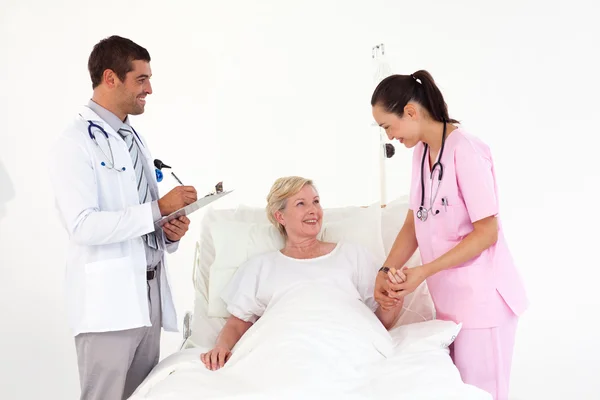 Усміхнений пацієнт лежить між доброзичливою медсестрою і лікарем — стокове фото