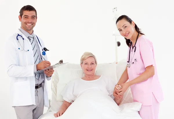Starsza kobieta między lekarzem i pielęgniarką — Zdjęcie stockowe