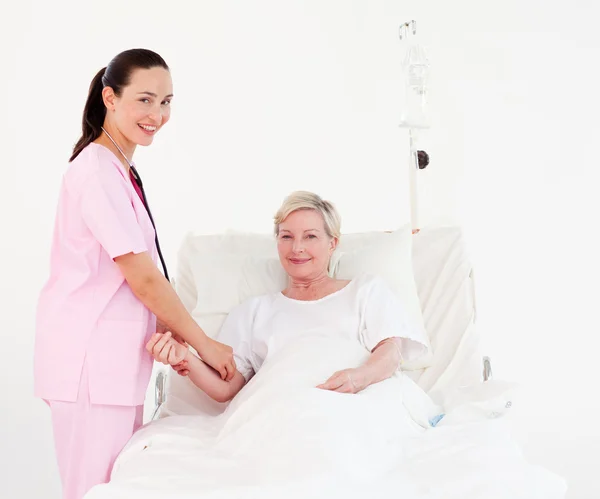 Mosolyogva nővér és a beteg néz a kamerába — Stock Fotó