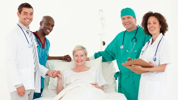 Команда больницы и пациентка улыбаются перед камерой — стоковое фото