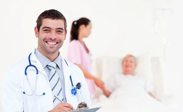Beautiful male doctor writing his diagnosis — Stock Photo, Image