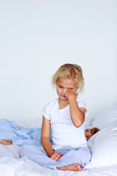 Tired girl sitting on the bed — Stock Photo, Image