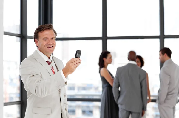 Hombre de negocios confiado sosteniendo un teléfono en el lugar de trabajo con su coll —  Fotos de Stock