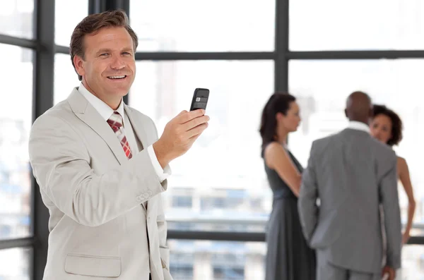 具有超凡魅力的商人在与他公司的工作场所手持电话 — 图库照片
