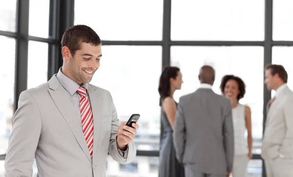 Латиноамериканский бизнесмен держит телефон на рабочем месте со своим коллегой — стоковое фото