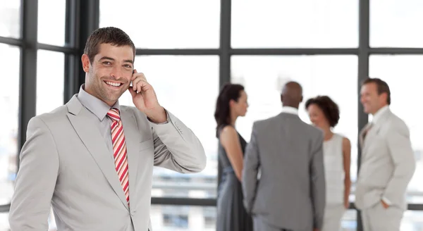 Joyful businessman holding a phone at workplace with his colleag — Stock Photo, Image
