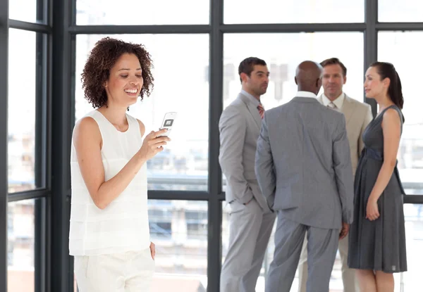 Empresaria sosteniendo un teléfono en el lugar de trabajo con sus colegas — Foto de Stock