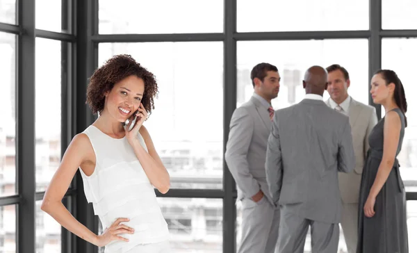 Bright Businesswoman holding a phone at workplace with his colle — Stock Photo, Image