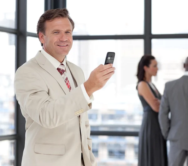 Šťastný podnikatel drží telefon na pracovišti s jeho colleagu — Stock fotografie