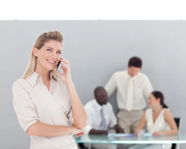 Mulher caucasiana falando ao telefone com sua equipe — Fotografia de Stock