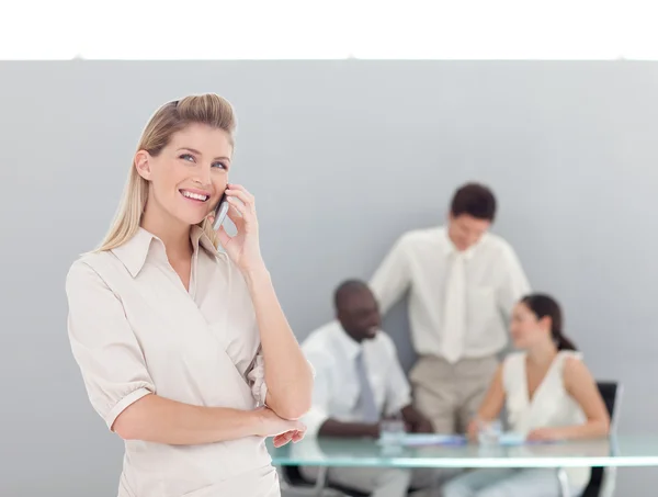 Sonriente mujer hablando por teléfono con su equipo — Foto de Stock