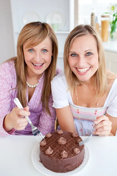 Glückliche Freunde mit einem Kuchen, der in die Kamera lächelt — Stockfoto