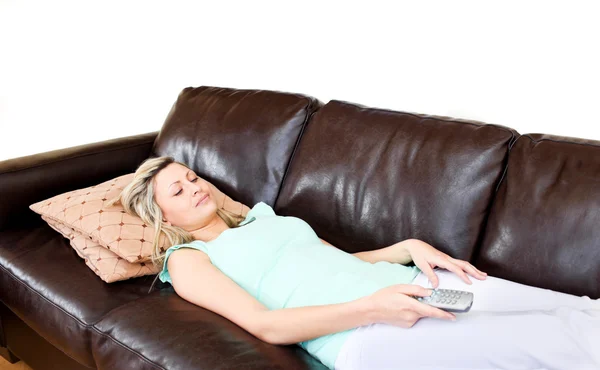 Mujer acostada tumbada en el sofá y mira la televisión — Foto de Stock