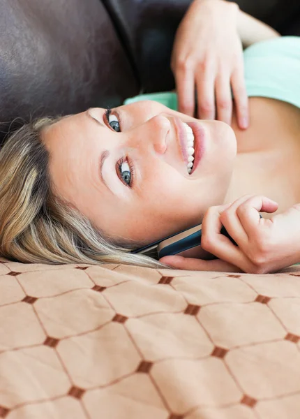 Радостная женщина лежит на диване и звонит — стоковое фото