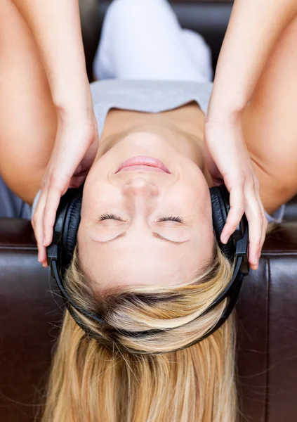 Спящая женщина лежит на диване и слушает музыку — стоковое фото