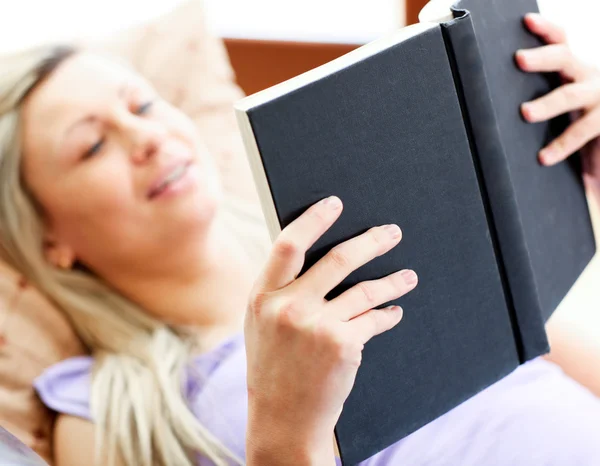 Λαμπερό γυναίκα βρίσκεται στον καναπέ και διαβάζοντας ένα βιβλίο — Φωτογραφία Αρχείου