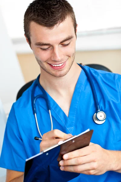 Médico carismático escribiendo en un portapapeles —  Fotos de Stock