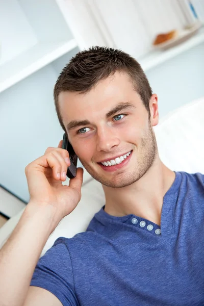 Attractive man sitting on sofa and talking on phone — Stock Photo, Image