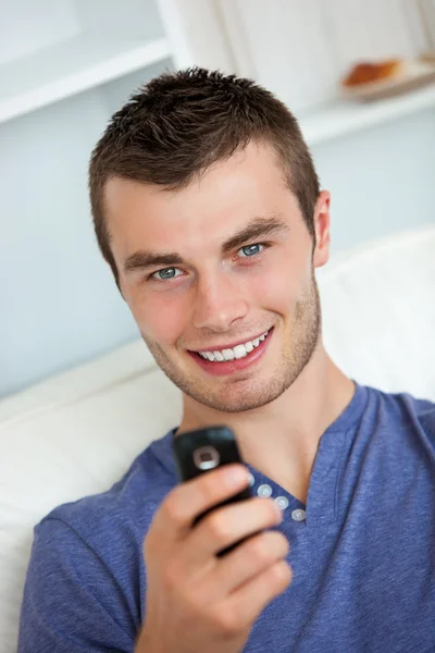 Cheerful man writing a message sitting on a couch — Stock Photo, Image