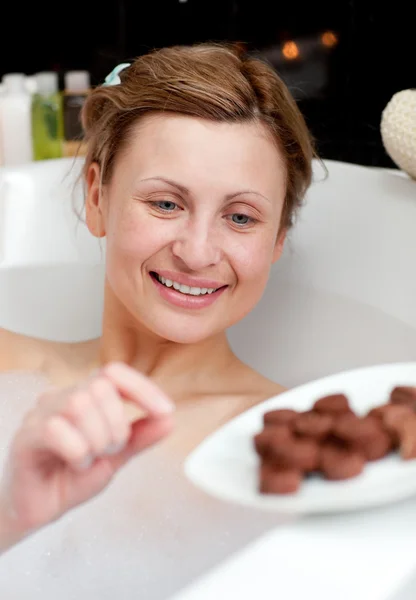 Φωτεινό γυναίκα τρώει σοκολάτα ενώ έχοντας ένα μπάνιο — Φωτογραφία Αρχείου