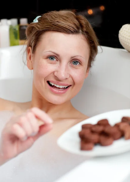 Mutlu bir kadın banyo yaparken yeme çikolata — Stok fotoğraf