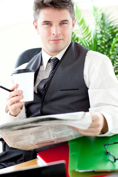 Serious businessman drinking a coffee while reading a newspaper — Stock Photo, Image