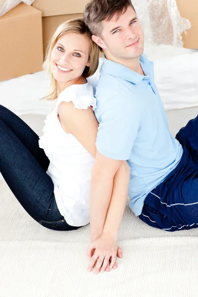 Casal jovem afetuoso sentado no chão na frente de caixas — Fotografia de Stock