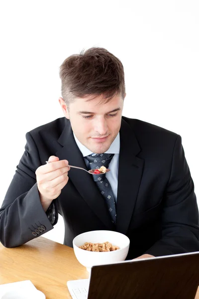 Młody biznesmen za pomocą laptopa, jedząc śniadanie — Zdjęcie stockowe