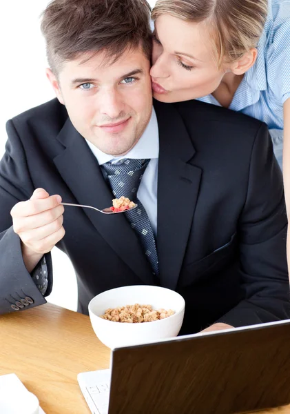 Empresário sorrindo tomando café da manhã enquanto esposa beijando seu chee — Fotografia de Stock