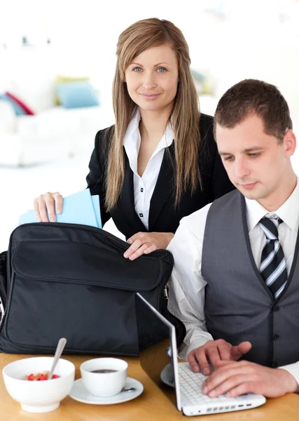 Businesswoman packing her bag businessman using laptop — Stock Photo, Image