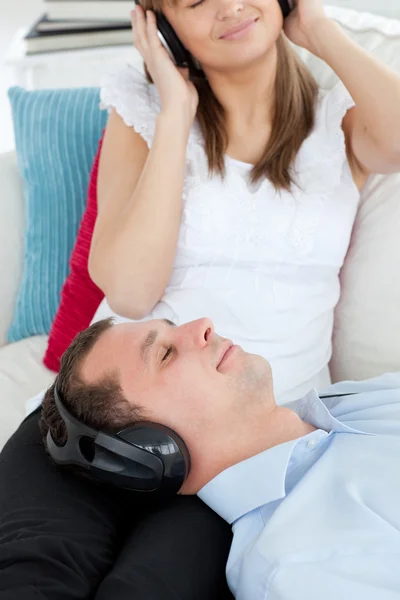 Close-up de um homem ouvindo música deitado no sofá com o seu — Fotografia de Stock