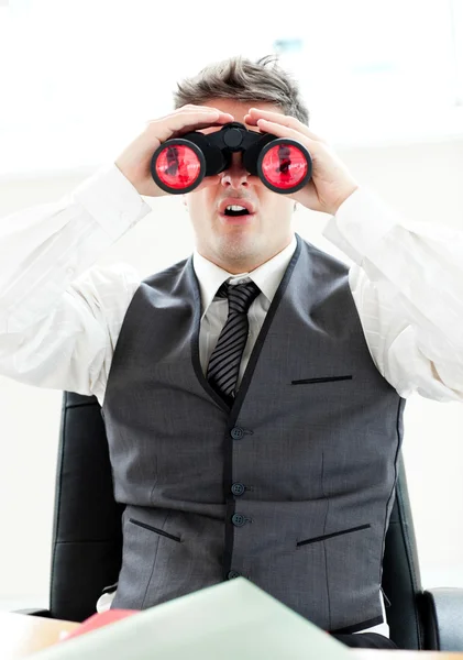 Empresário impressionado olhando através binóculos sentado em seu — Fotografia de Stock