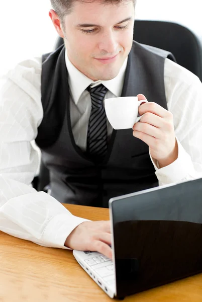 Feliz joven empresario mirando su portátil sosteniendo un café — Foto de Stock
