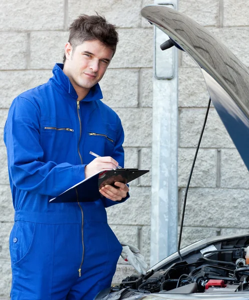 Attractive mechanic writing on a clipoard — Stock Photo, Image