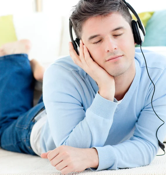 Avslappnad man liggande på golvet och lyssnar på musik — Stockfoto