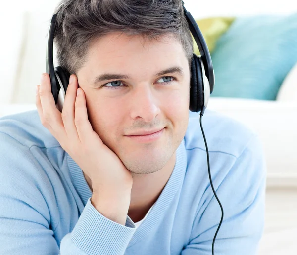 Portrait of a positive man with headphones lying on the floor — Stock Photo, Image