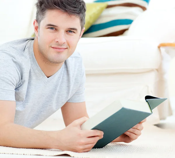 Happy young man looking at the camera holding a book — Stock Photo, Image
