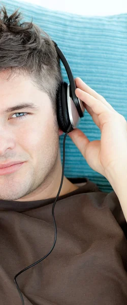 Okouzlující mladý muž poslouchá hudbu se sluchátky — Stock fotografie