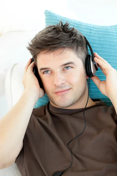 Joven sonriente con auriculares escuchando música — Foto de Stock