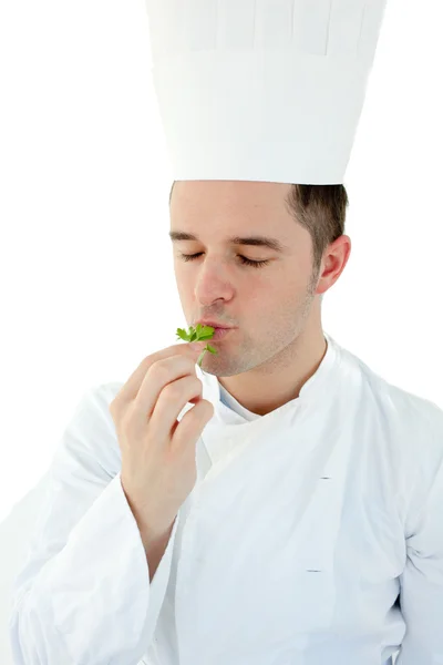 Cocinero joven con los ojos cerrados degustando una hierba contra el backgro blanco —  Fotos de Stock