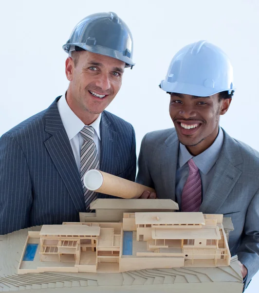 Uśmiechający się inżynierów z twardym kapelusze gospodarstwa dom modelu — Zdjęcie stockowe